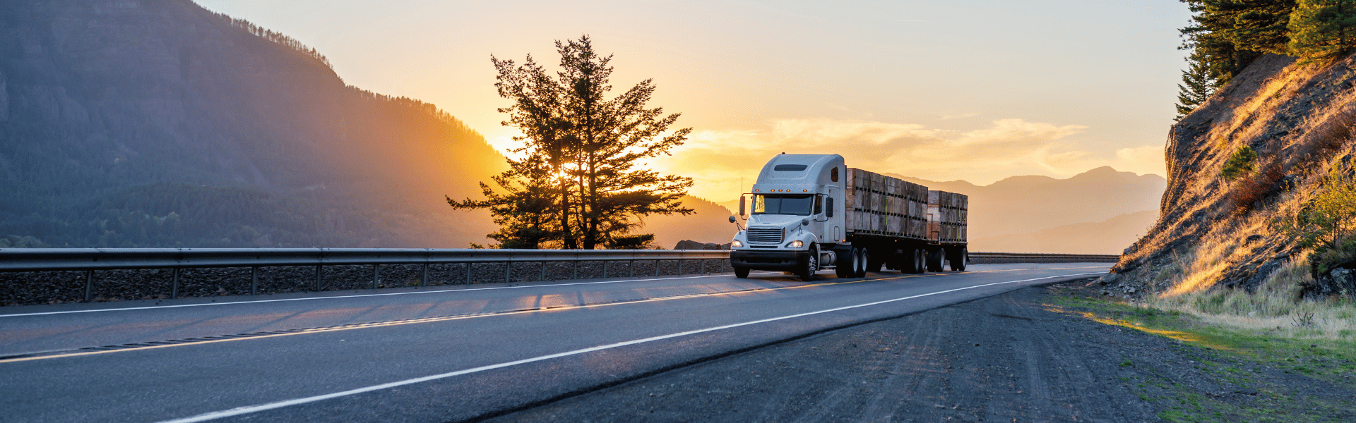 semi driving down a mountain highway at sunset