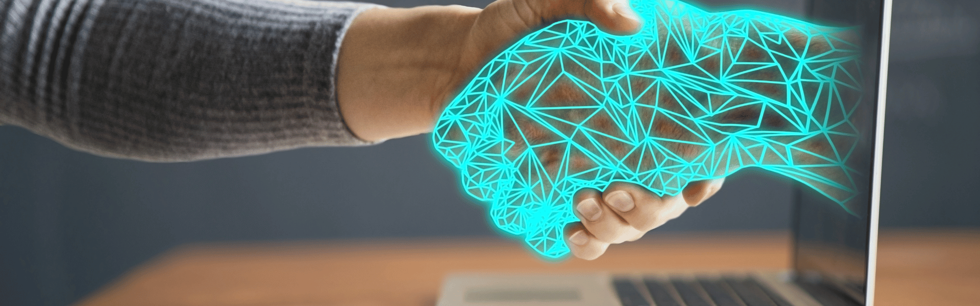 Human hand shaking hands with artificial hand coming out of computer