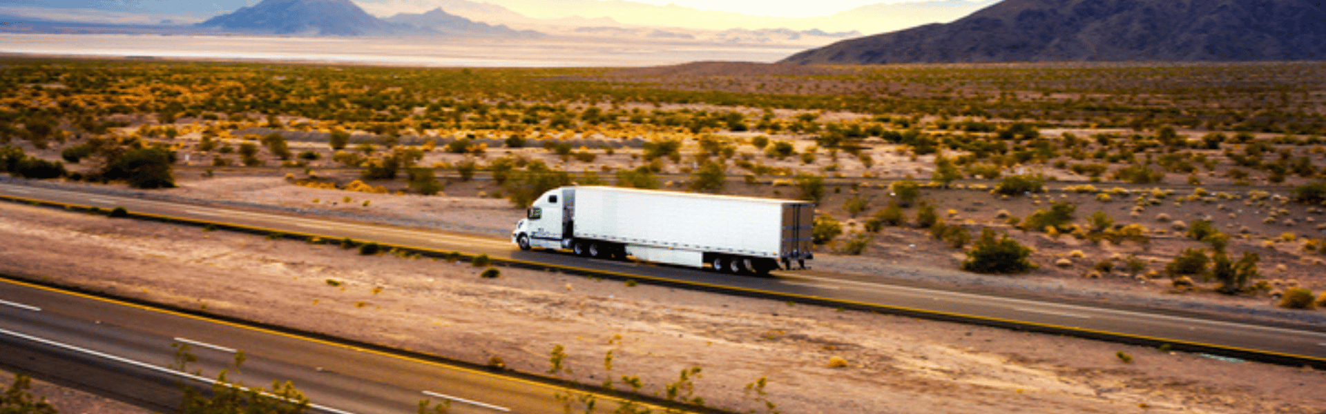 semi truck on open highway with mountains in the background