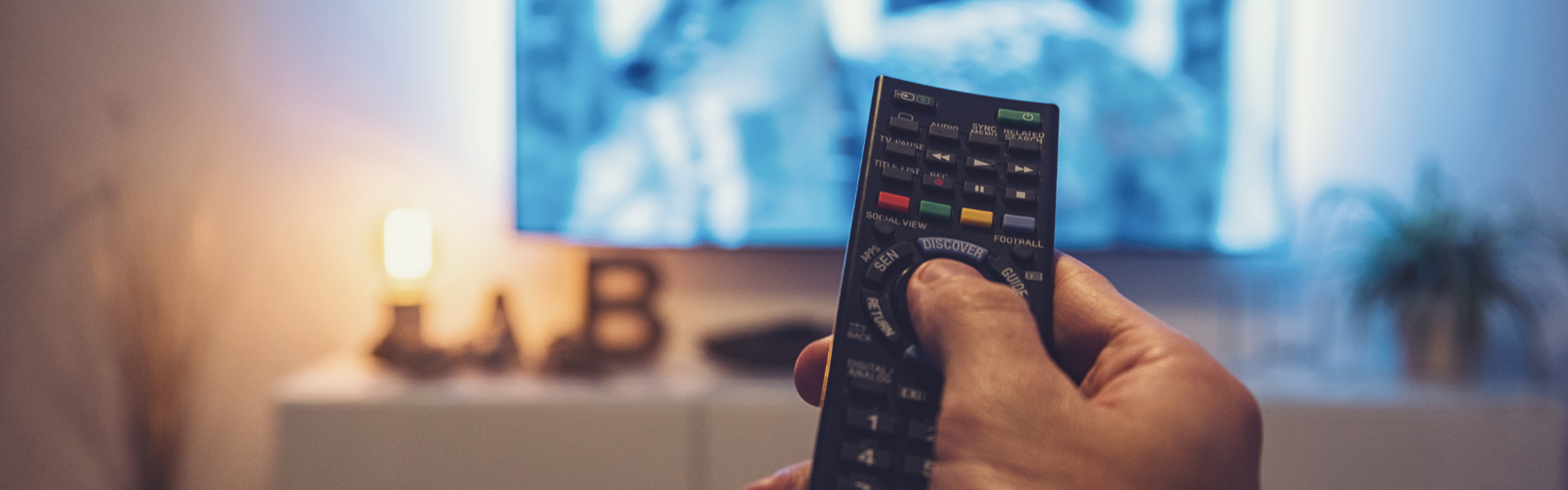 man holding remote towards television set