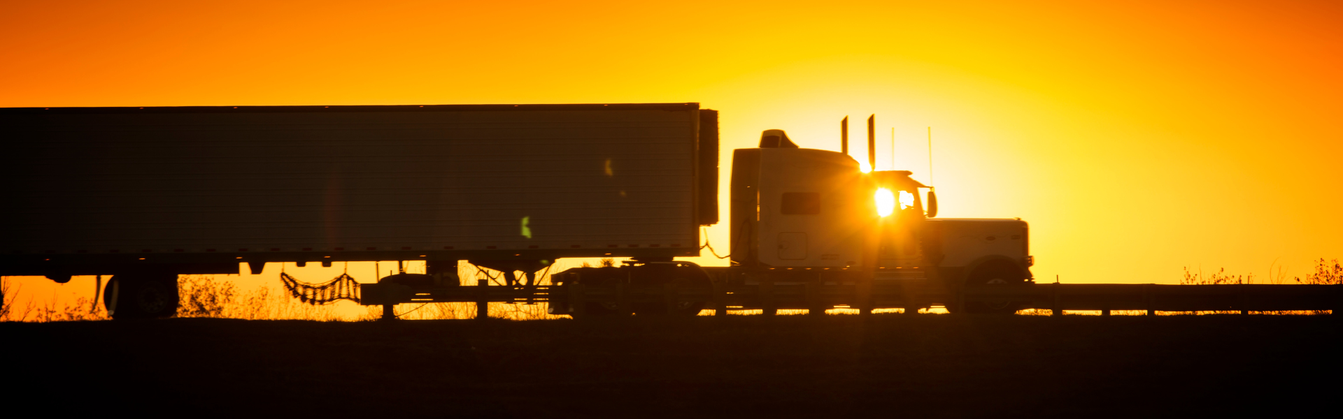 semi truck silhouetted in a sunset