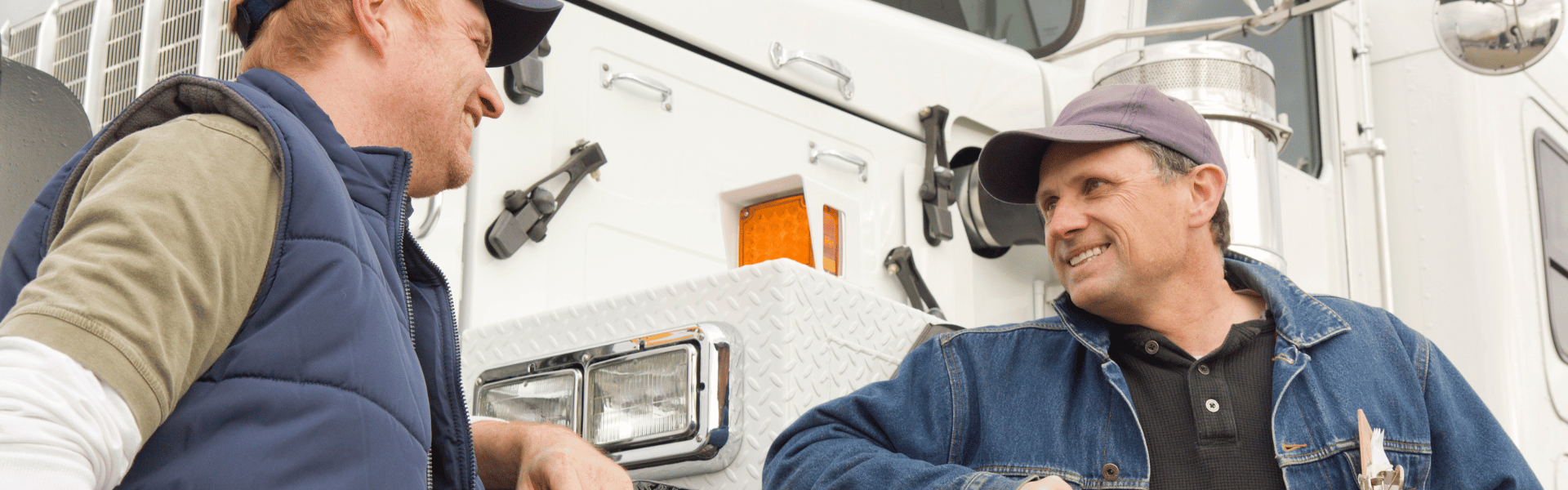 two men standing in front of a semi truck