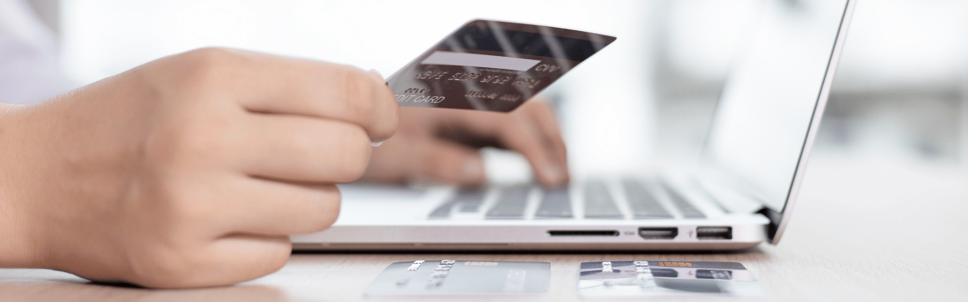 hand holding credit card over laptop keyboard for online shopping