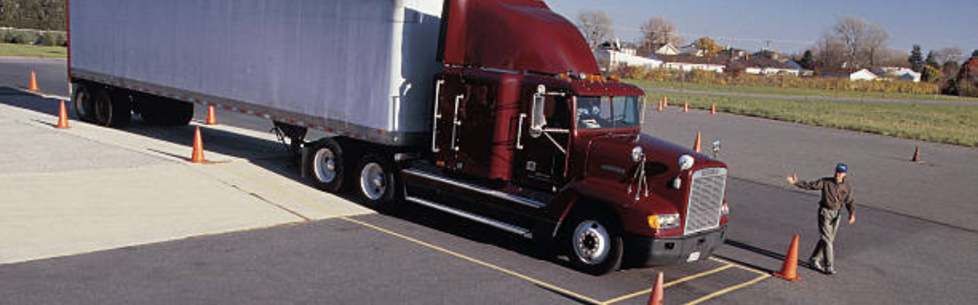 semi truck being guided by man into coned area