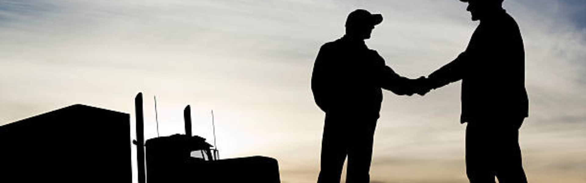 silhouettes of two men shaking hands next to a semi truck