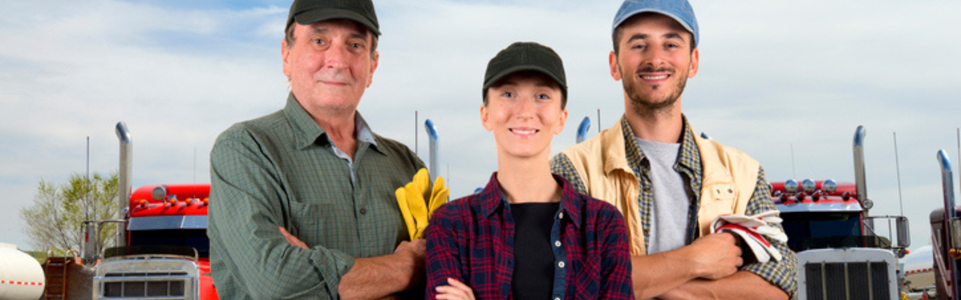 man with younger woman and younger man standing in front of semi trucks