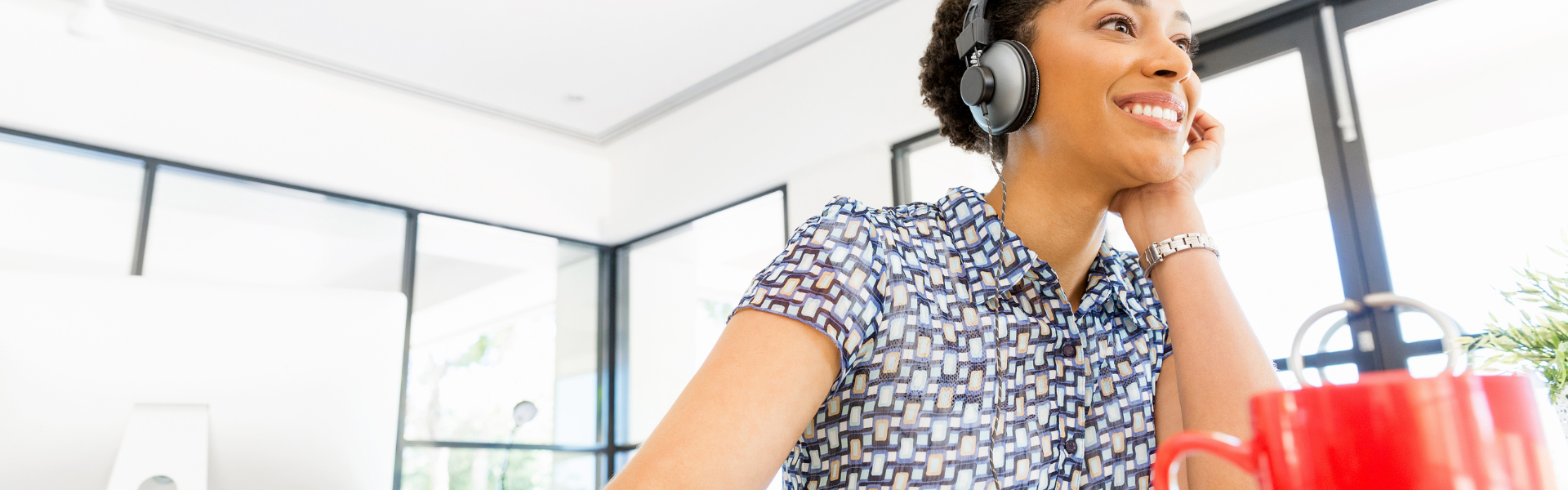 woman in office wearing headphones with coffee mug