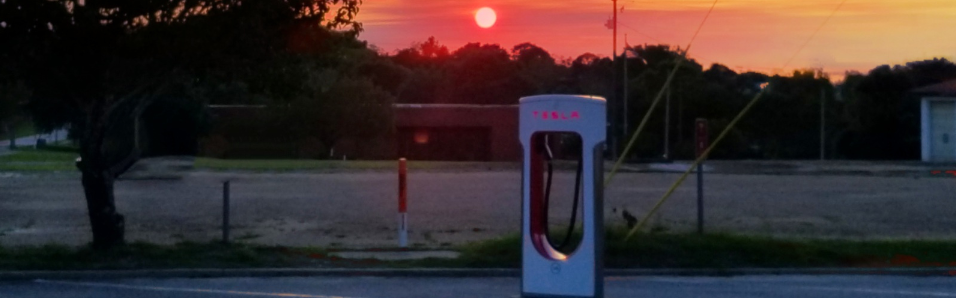 tesla charger with sunset in background