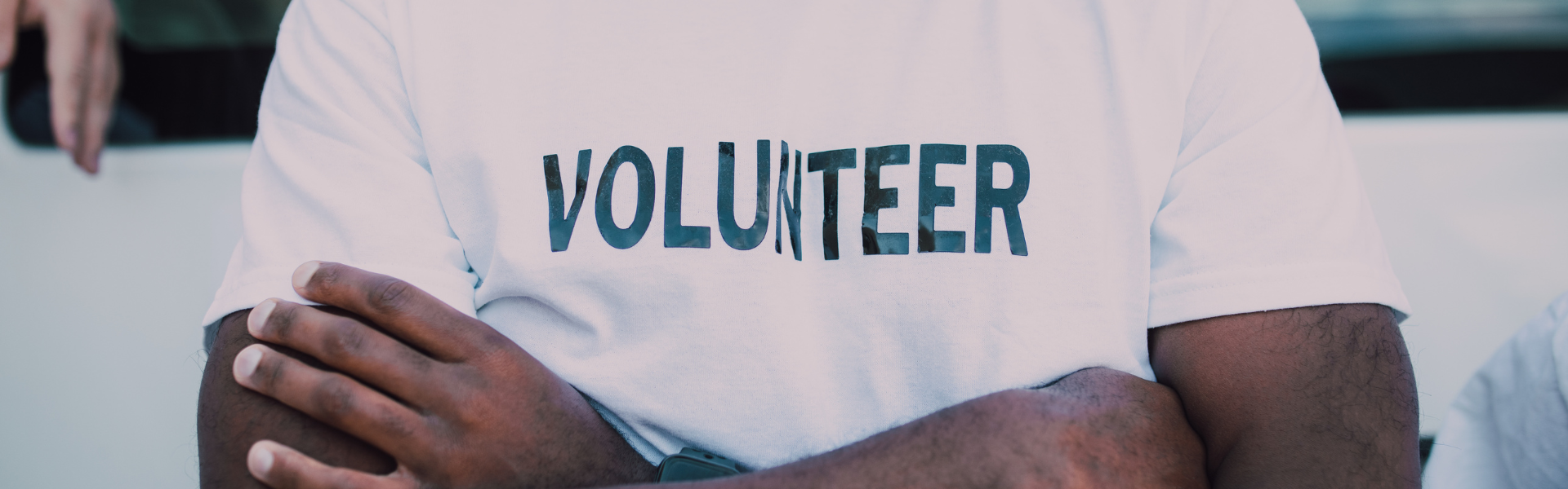 black man in volunteer shirt with crossed arms