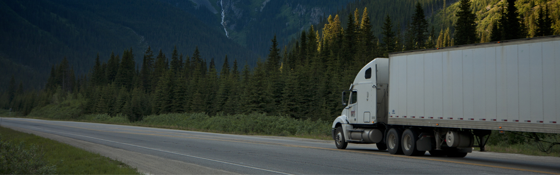 semi truck driving on road through mountains