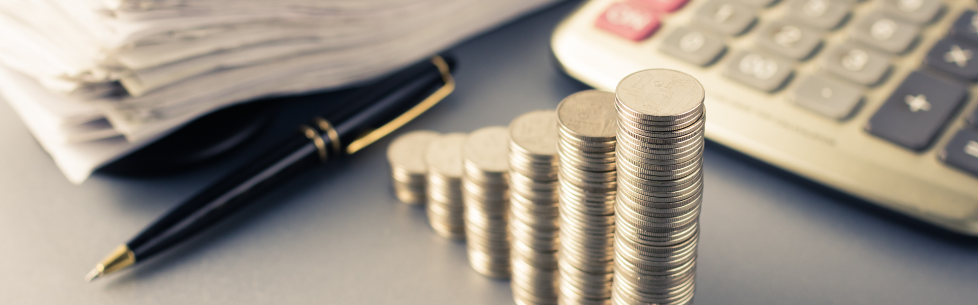 calculator, pen, papers, and growing stacks of coins