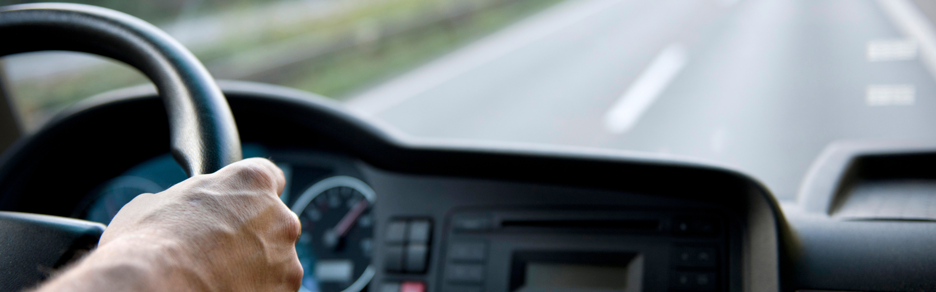 driver behind the wheel of semi truck looking forward through dash