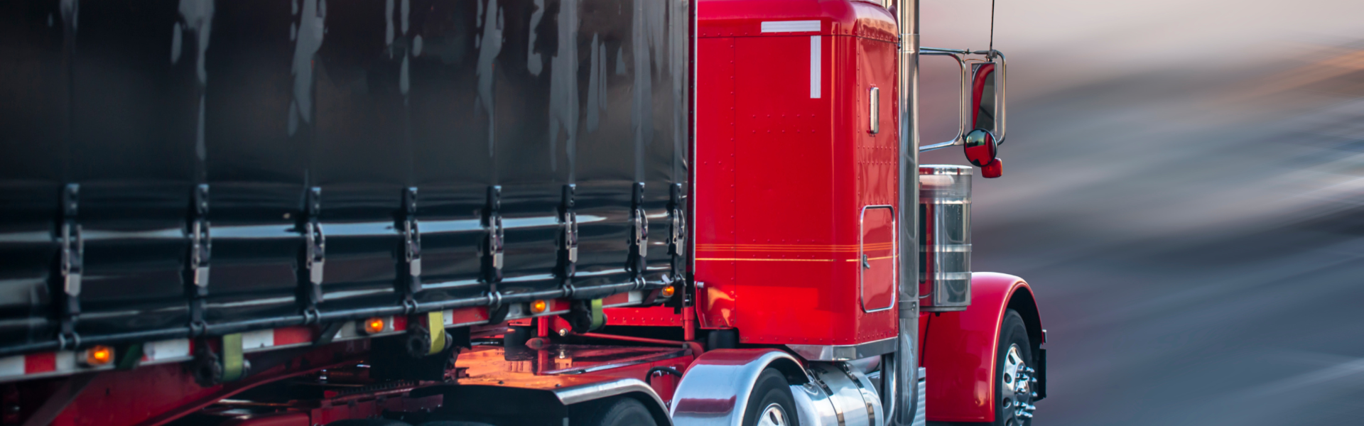 red semi truck with black trailer on road