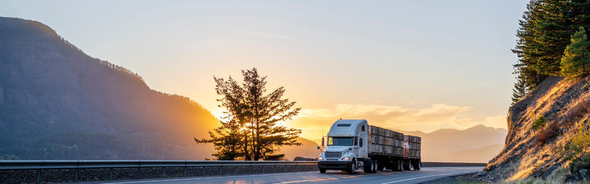 semi truck on road at sunset with mountain in background