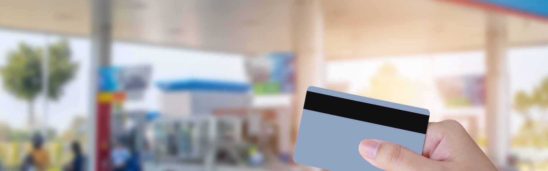 credit card in foreground and fuel pumps in background