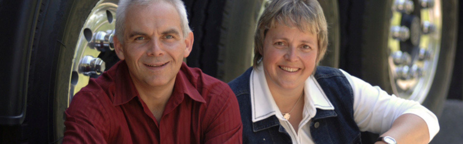 older couple sitting in front of semi truck tires