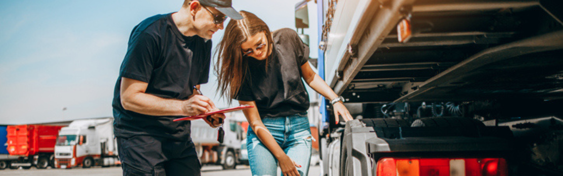 man and woman looking at semi truck with clipboard