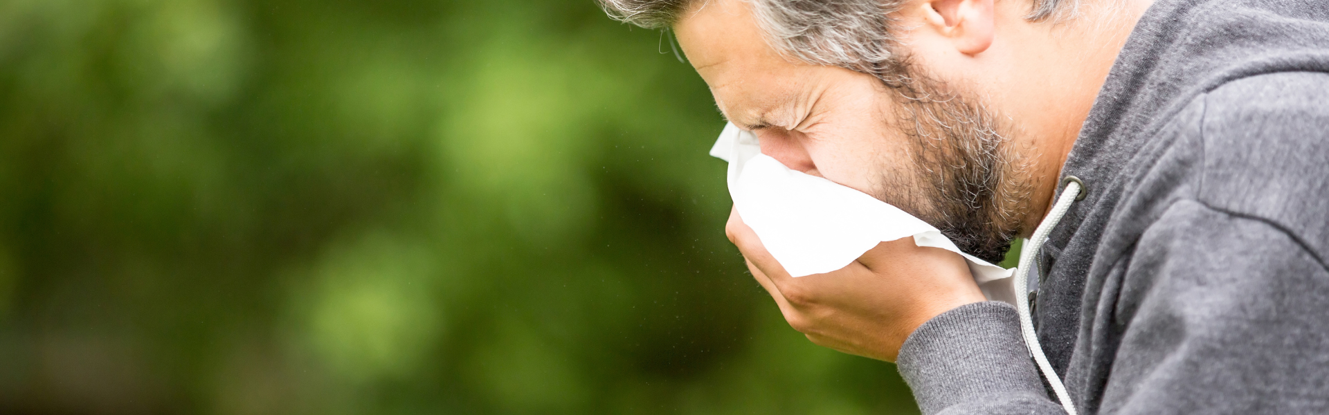 man sneezing into tissue