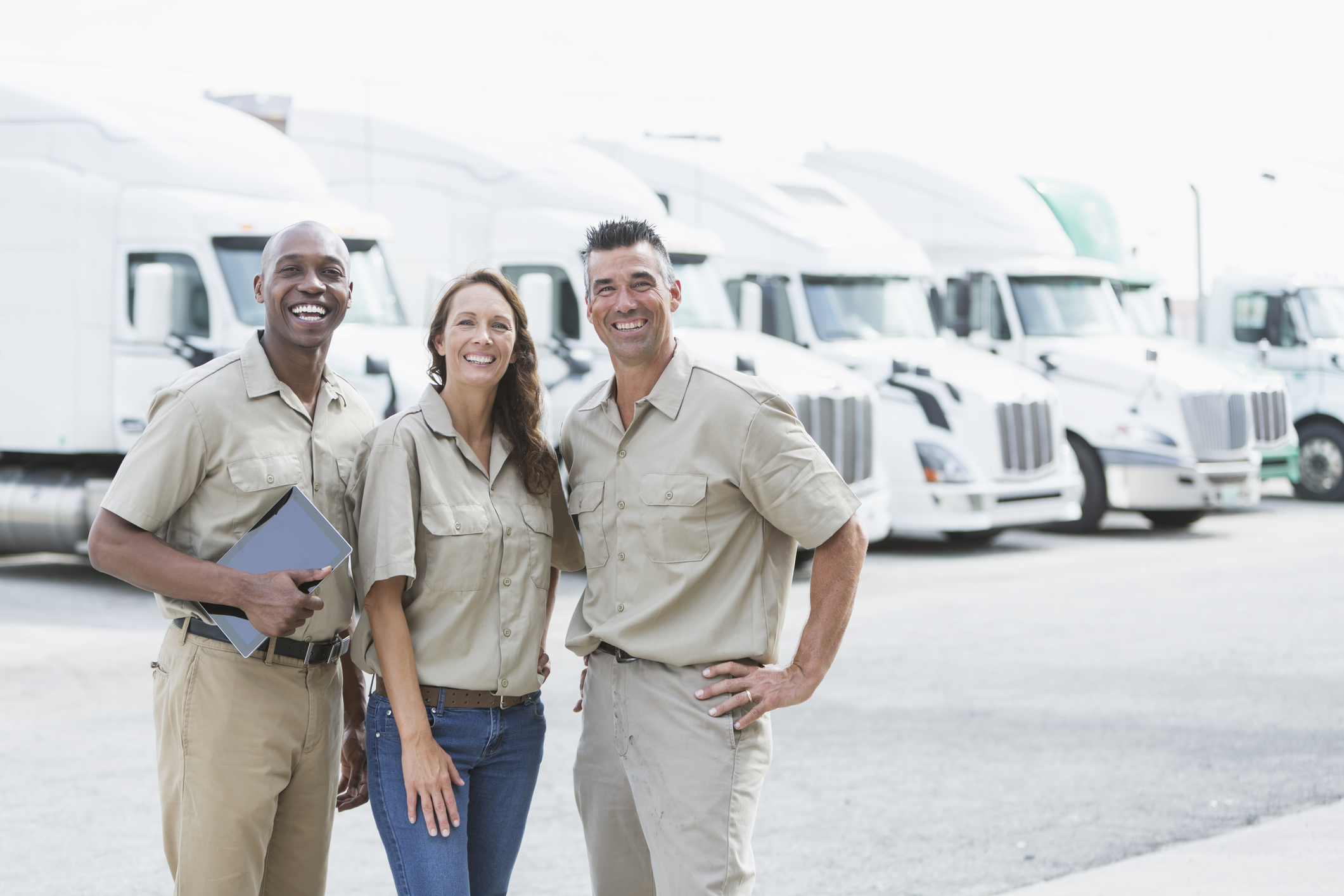 Three workers in front of semi-trucks