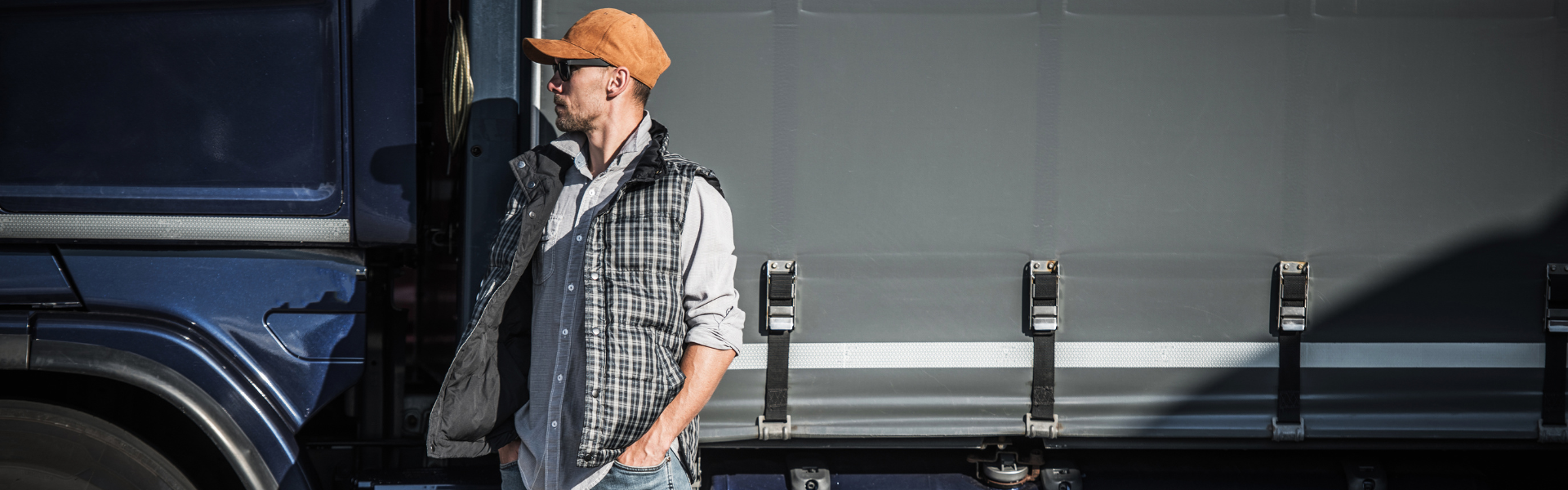 man in hat standing in front of semi truck