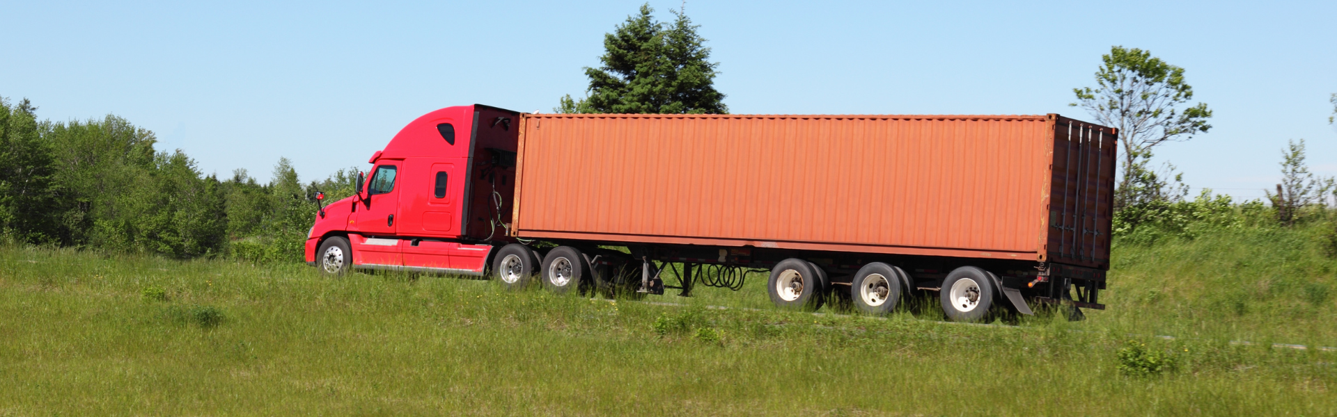 red semi truck with orange trailer on road