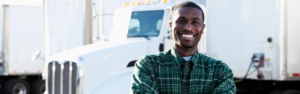 smiling black man standing in front of semi truck