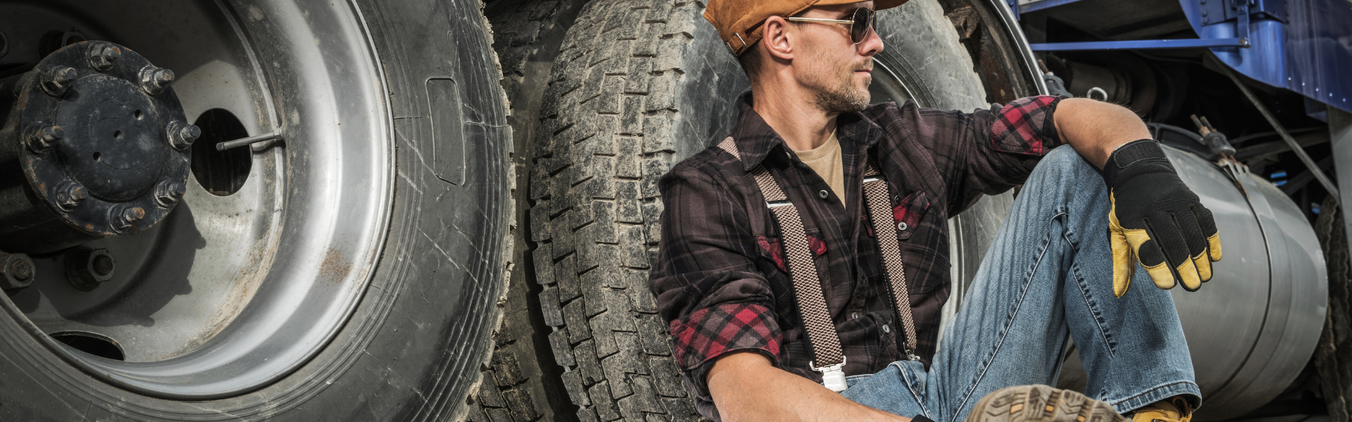 trucker leaning up against semi truck wheels