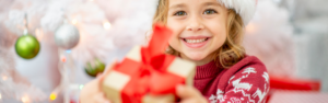little girl holding out holiday gift