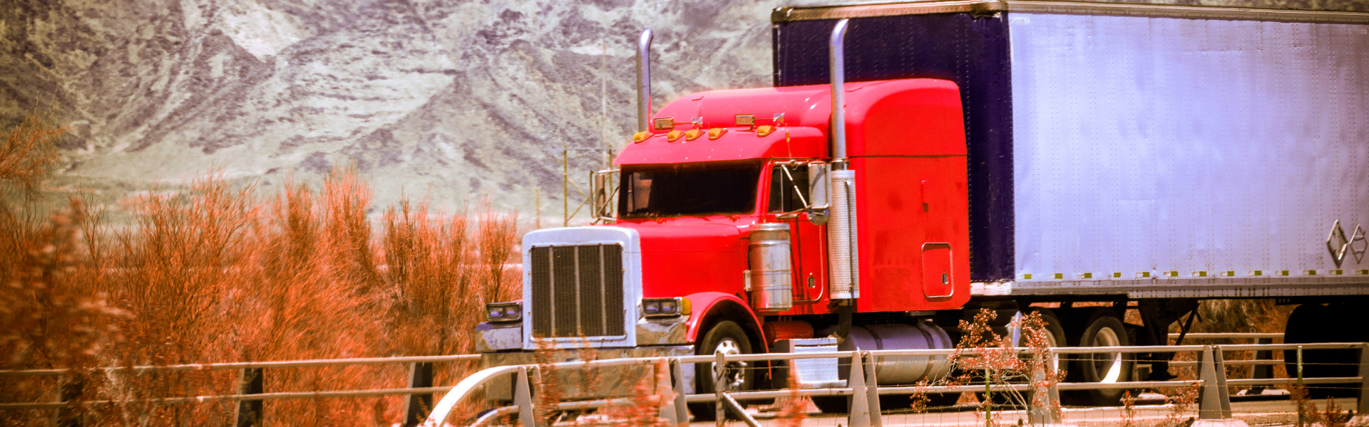 red semi truck on road with mountain in background