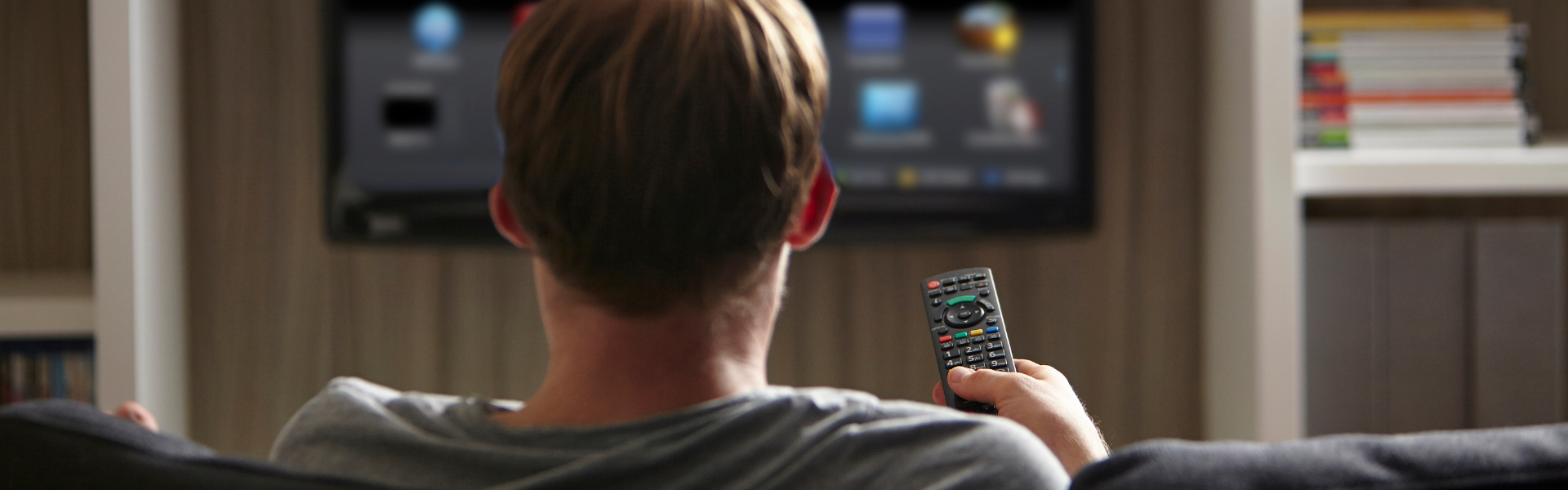 man holding tv remote with tv in background