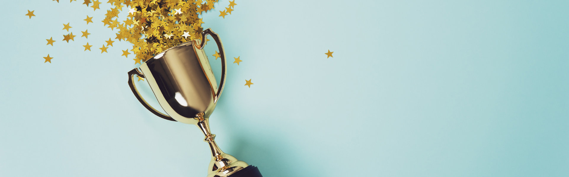 confetti stars spilling out of gold trophy on light blue background