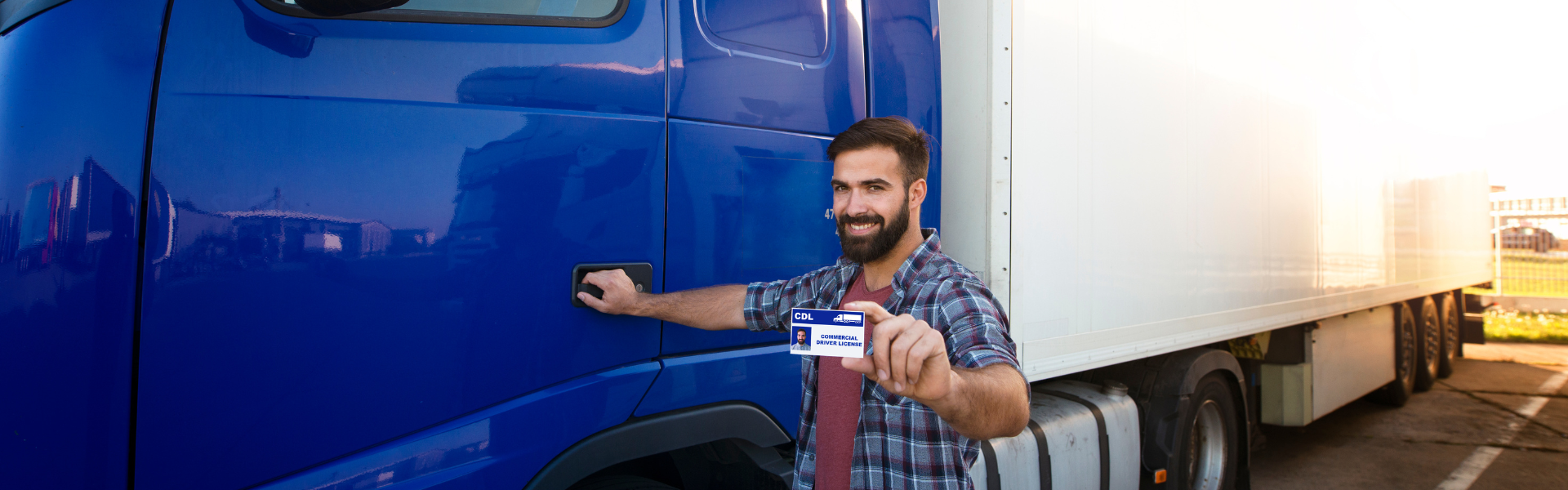 man next to semi truck holding up cdl