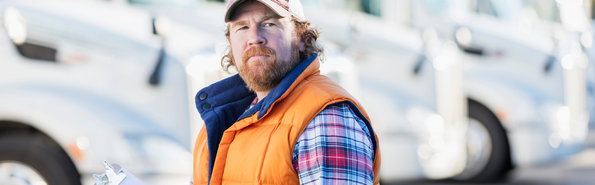 Man in orange vest standing in front of semi trucks
