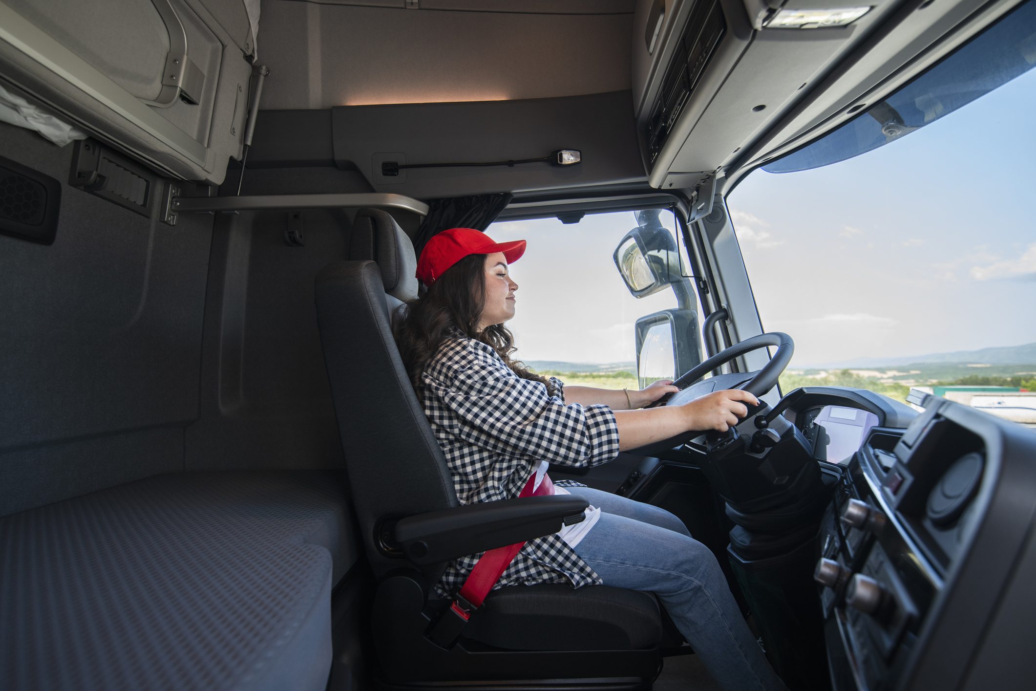 Happy female truck driver driving on a sunny day.Trucker occupation.