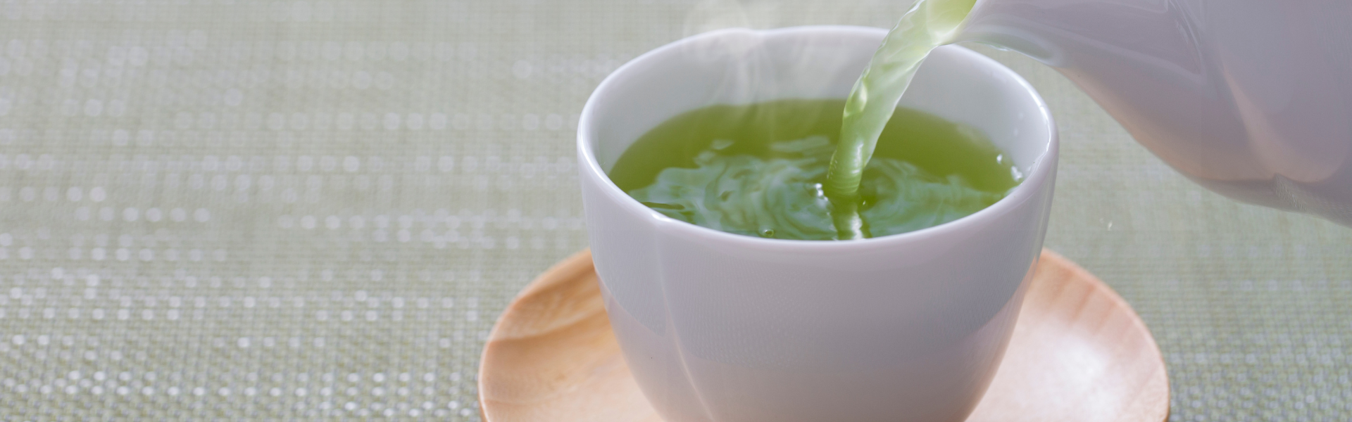 green tea being poured into white tea cup