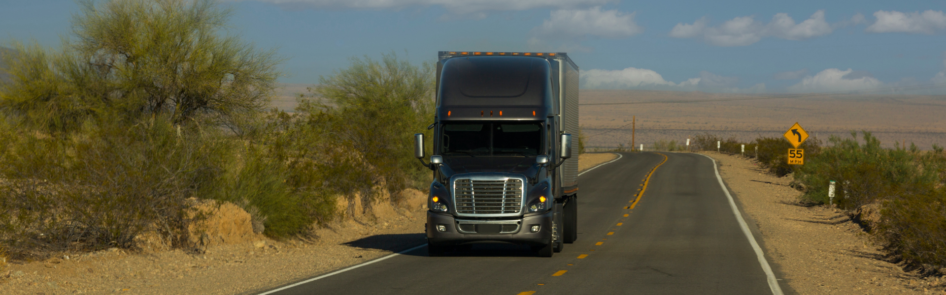 Gray semi truck on two lane road