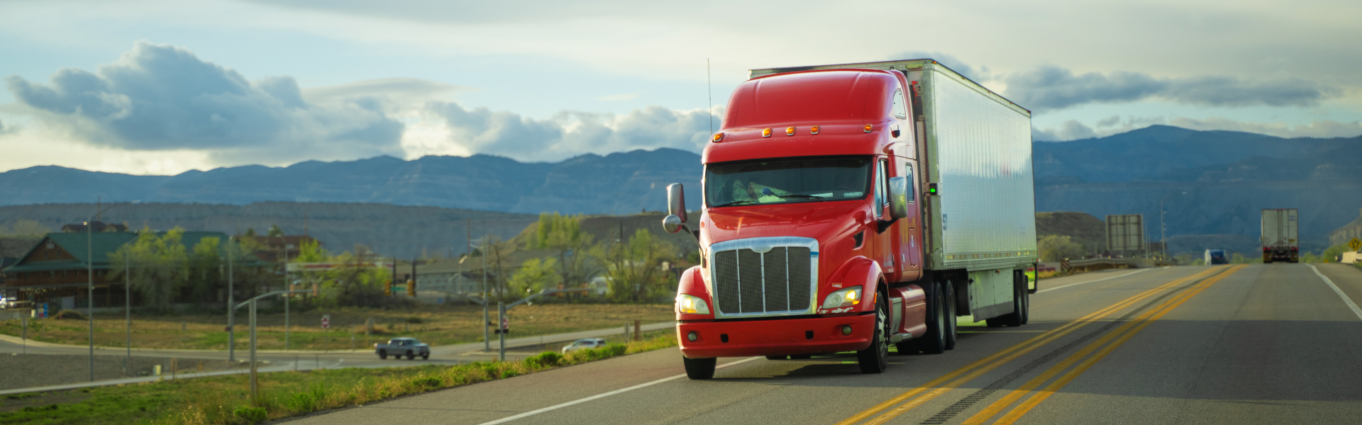 red semi truck on road with mountains in background
