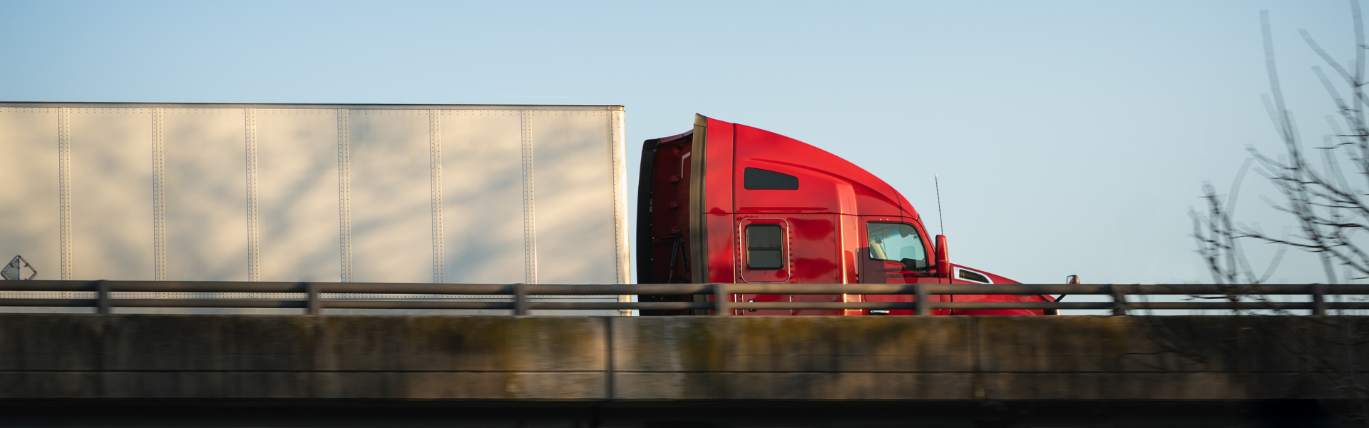 red semi truck with white trailer on bridge