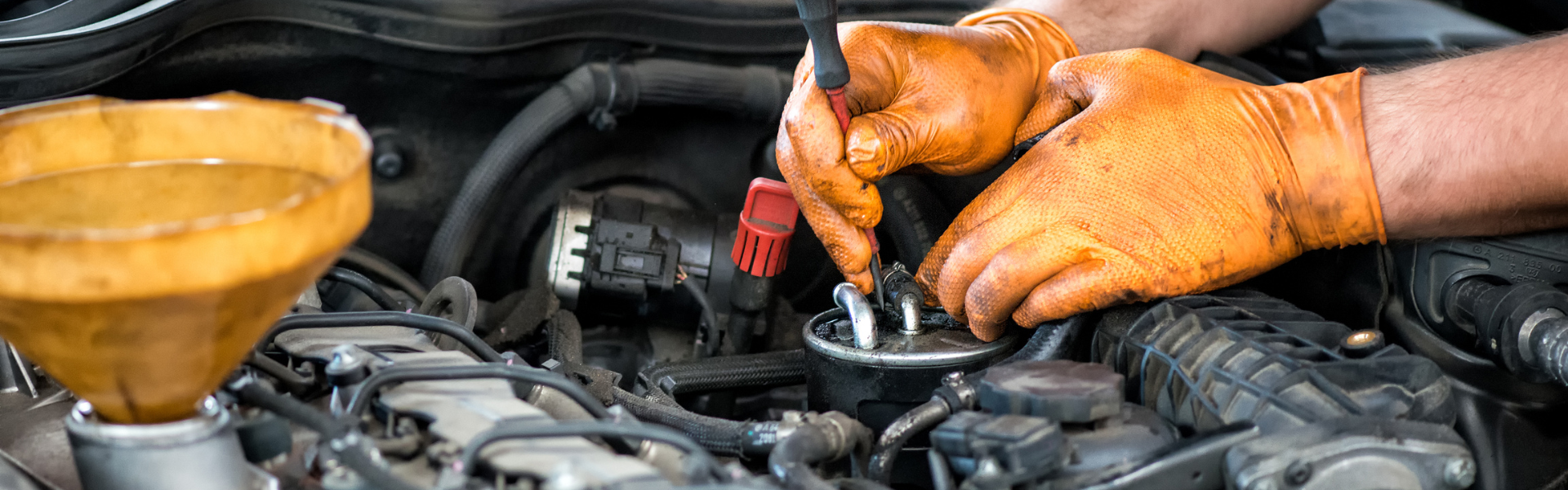 mechanic wearing orange gloves working on engine