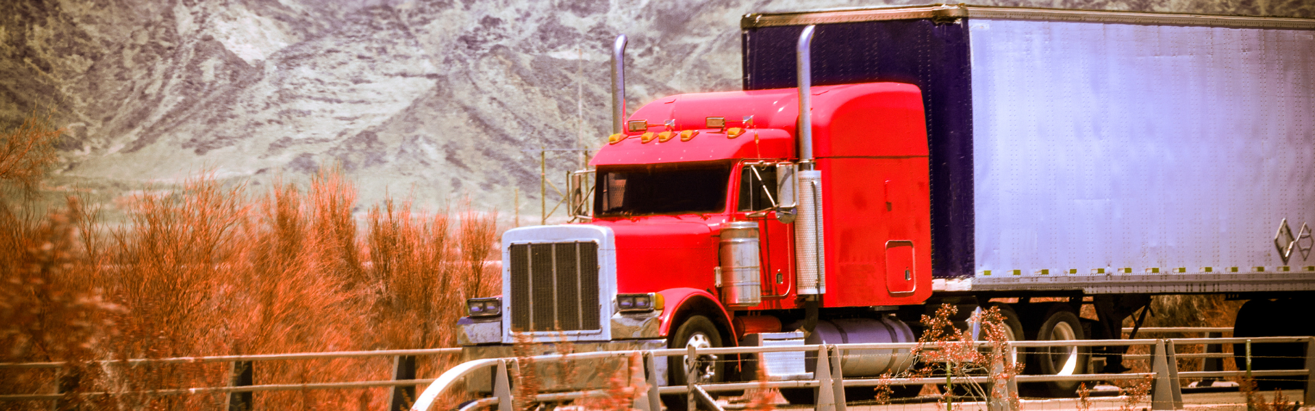 red semi truck with white trailer on road with mountains in background