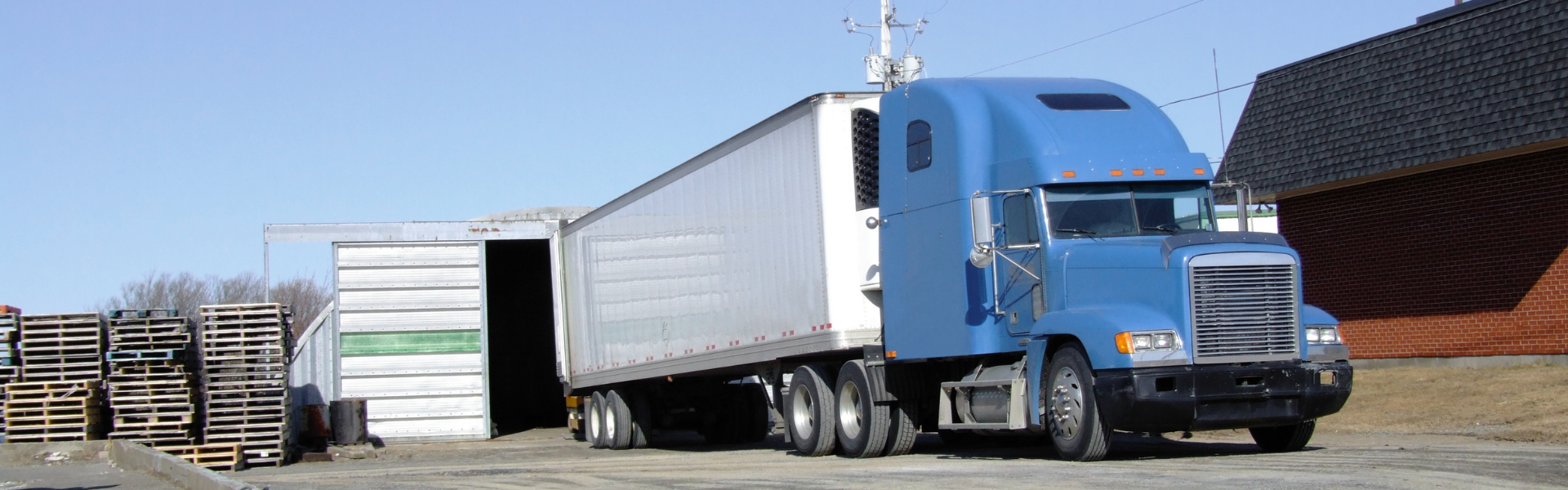 blue semi truck with white trailer ready to unload