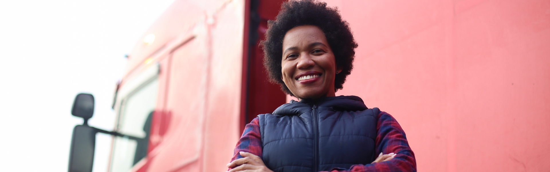 black woman standing in front of red semi truck