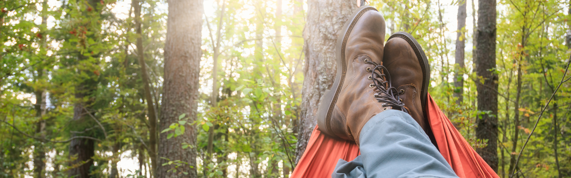 man wearing work boots relaxing in hammock in woods