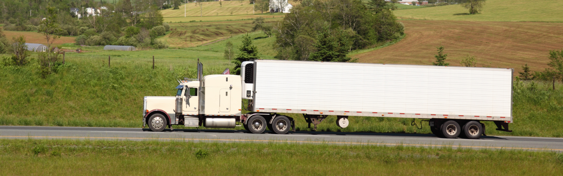 semi truck on road with fields in background