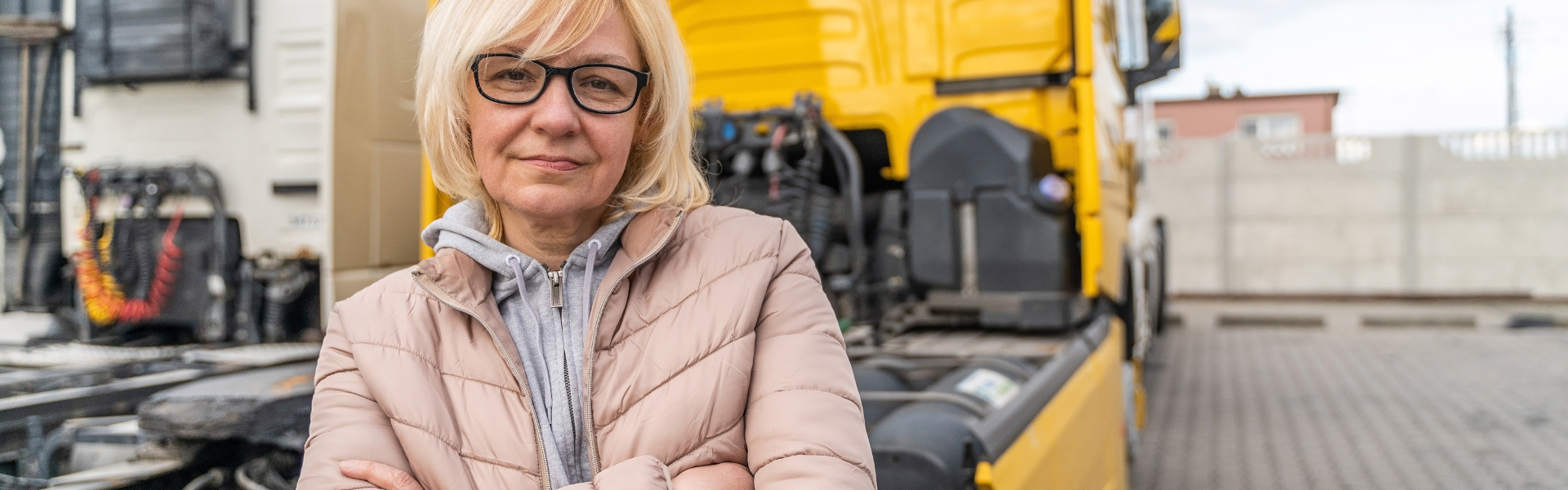 woman standing in front of yellow semi truck