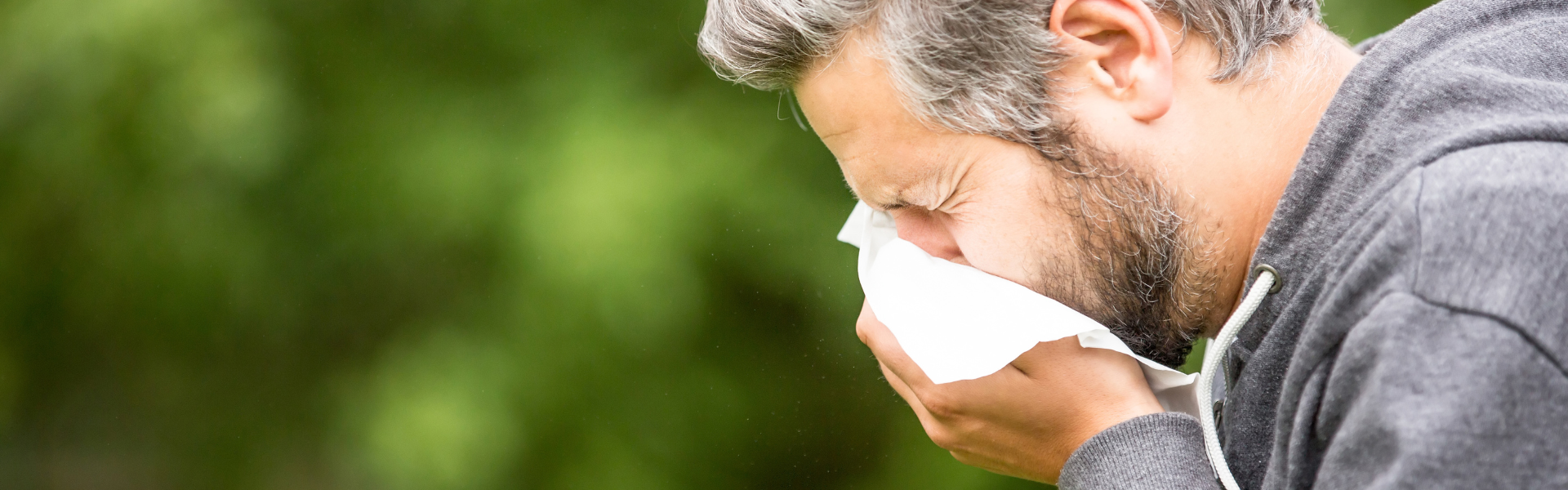 man sneezing into tissue