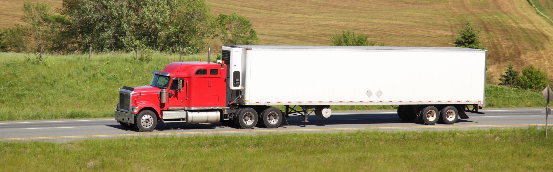 red semi truck with white trailer on road