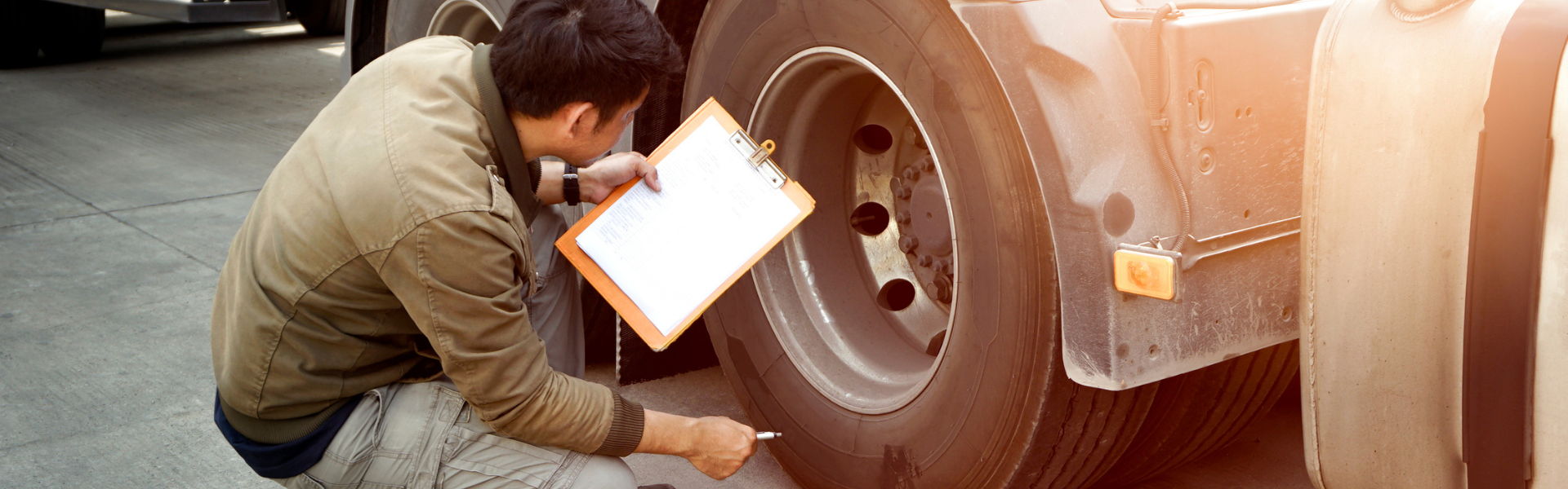 man with clipboard near semi truck tires