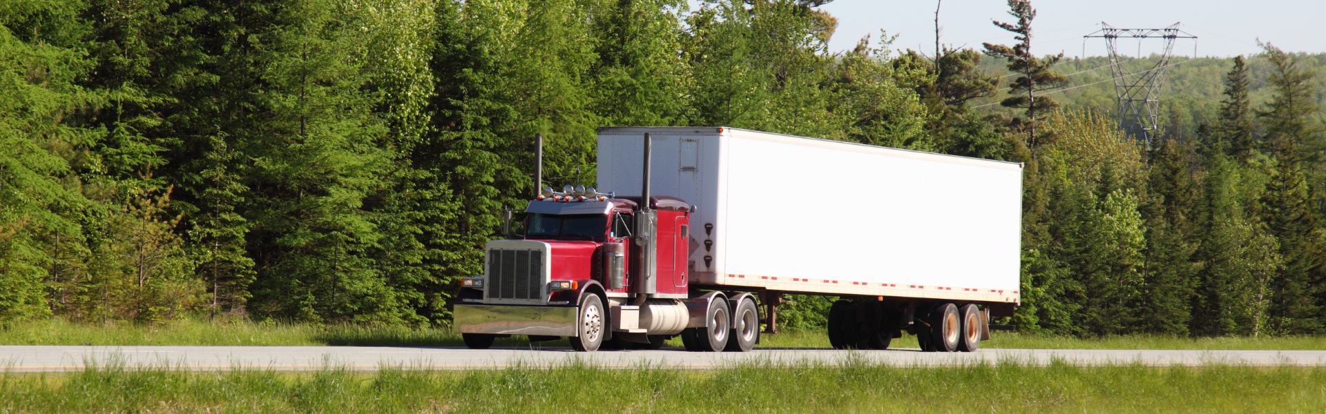 red semi truck pulling white trailer on road