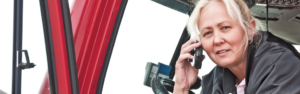 woman in cab of semi truck with cell phone
